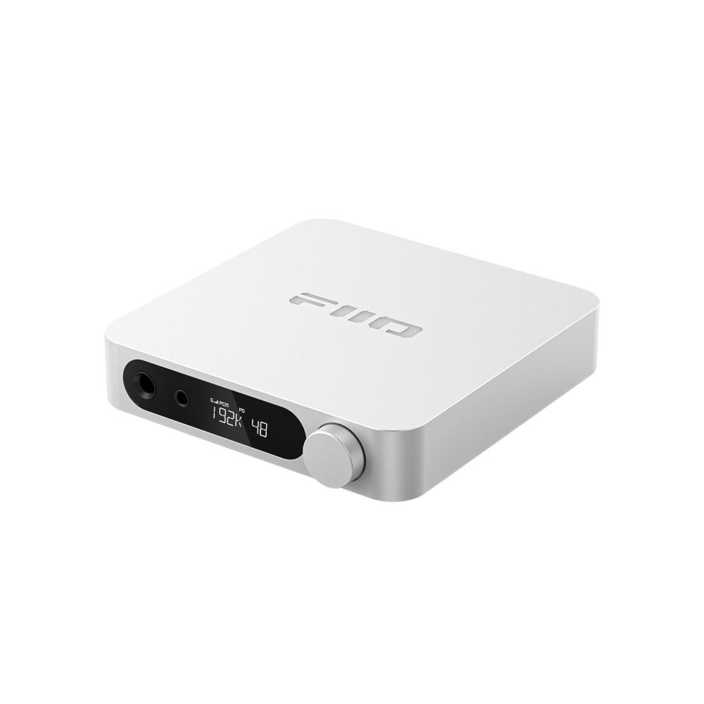 FiiO K11 desktop DAC and headphone amp in silver, front three-quarter view showing the headphone outputs, LCD display and volume knob